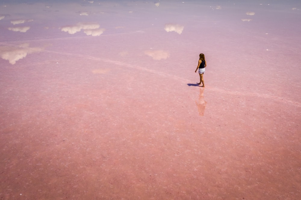a woman standing in the middle of a pink lake