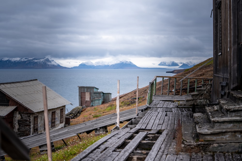 an old wooden building sitting on top of a hill next to a body of water