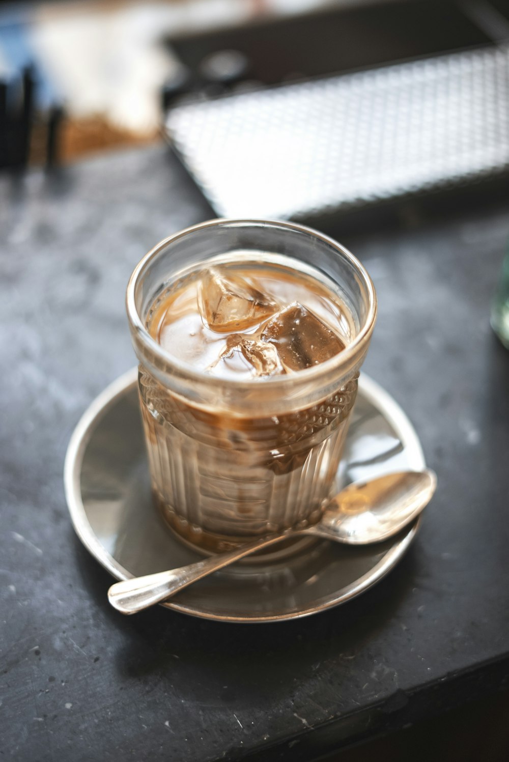 a cup of iced coffee on a saucer with a spoon