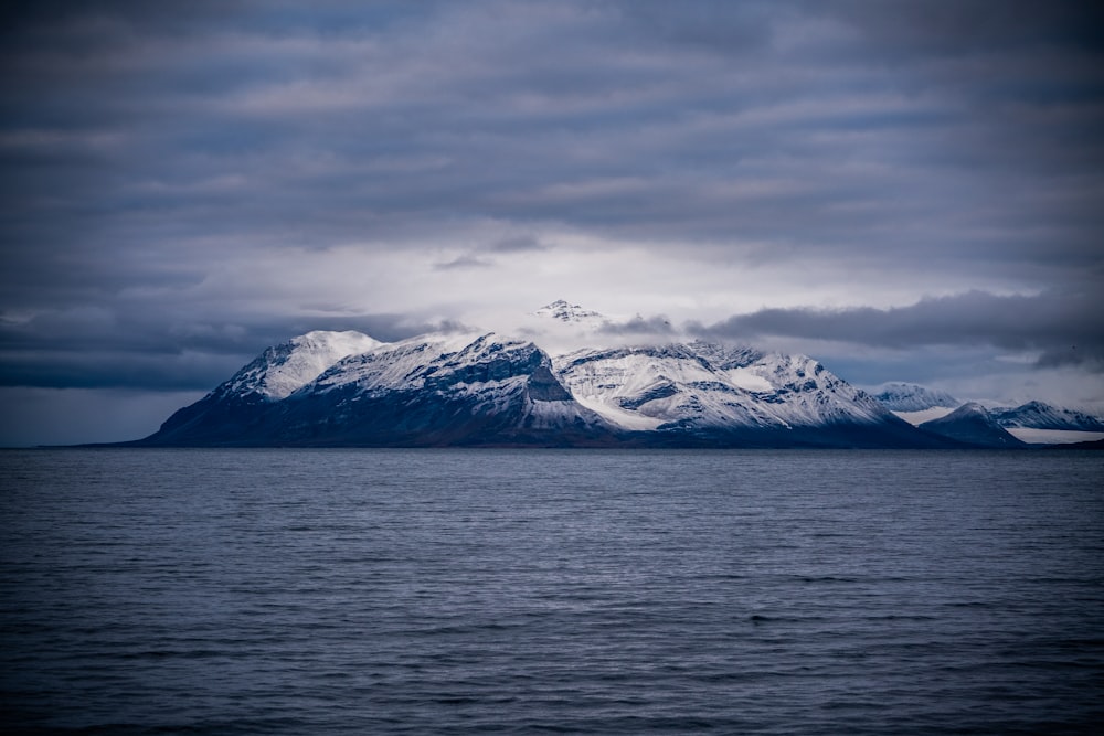 a large mountain covered in snow on top of a body of water