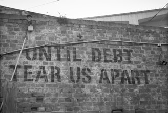a sign on a brick wall that says until debt tears apart