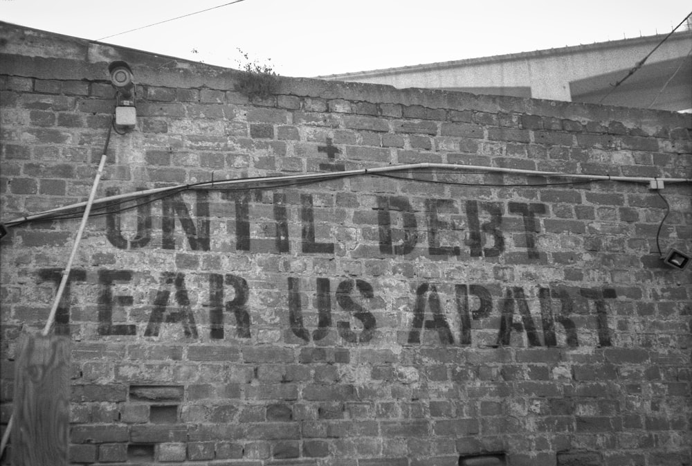 a sign on a brick wall that says until debt tears apart