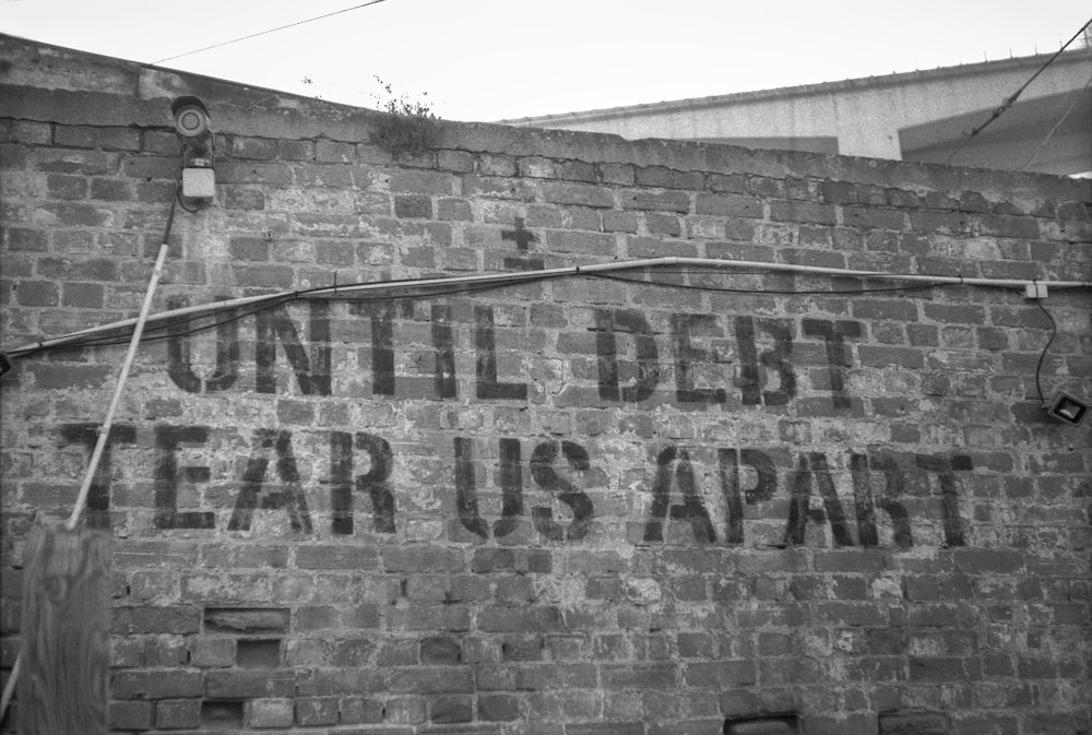 Un panneau sur un mur de briques qui dit jusqu’à ce que la dette se déchire