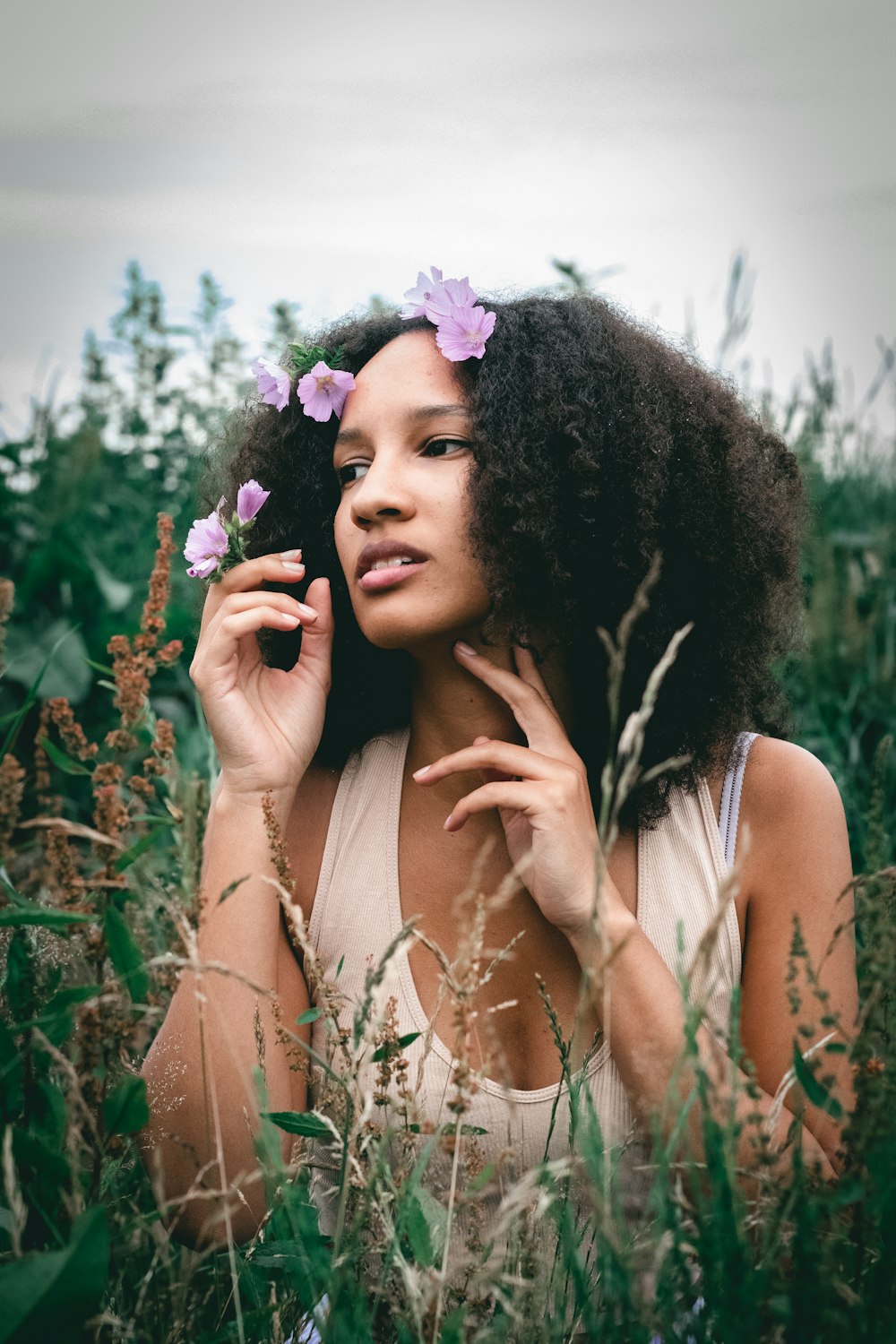 a woman standing in a field with flowers in her hair