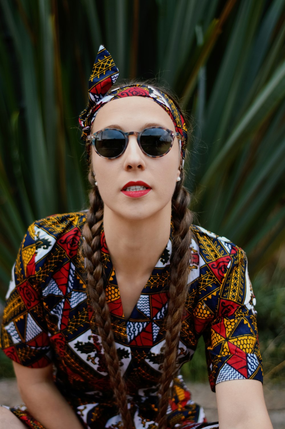 a woman sitting on the ground wearing sunglasses and a headband