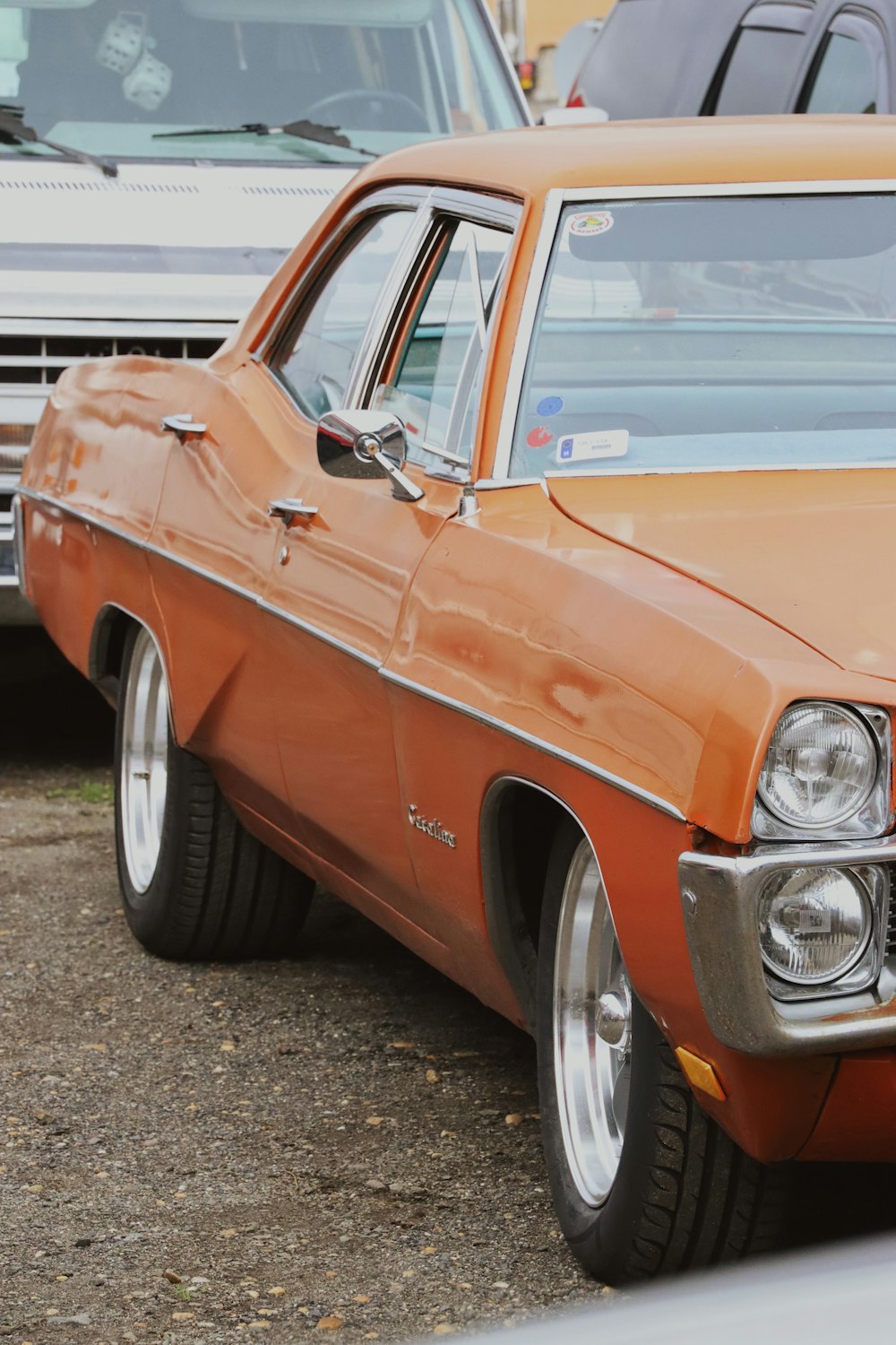 an orange car parked in a parking lot next to other cars