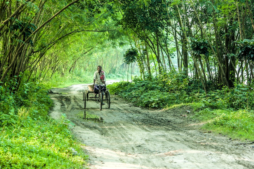 a man riding a bike down a dirt road