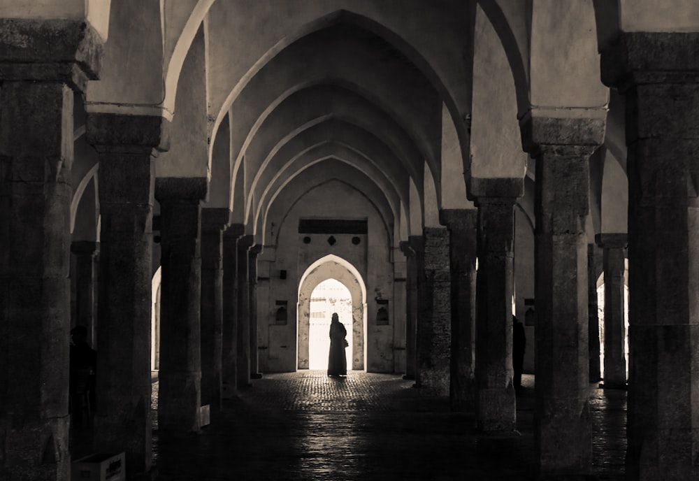 una foto in bianco e nero di una persona in piedi in un corridoio