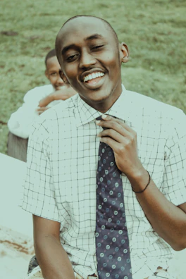 A candid moment of Lucas adjusting his tie with a gentle smile.
