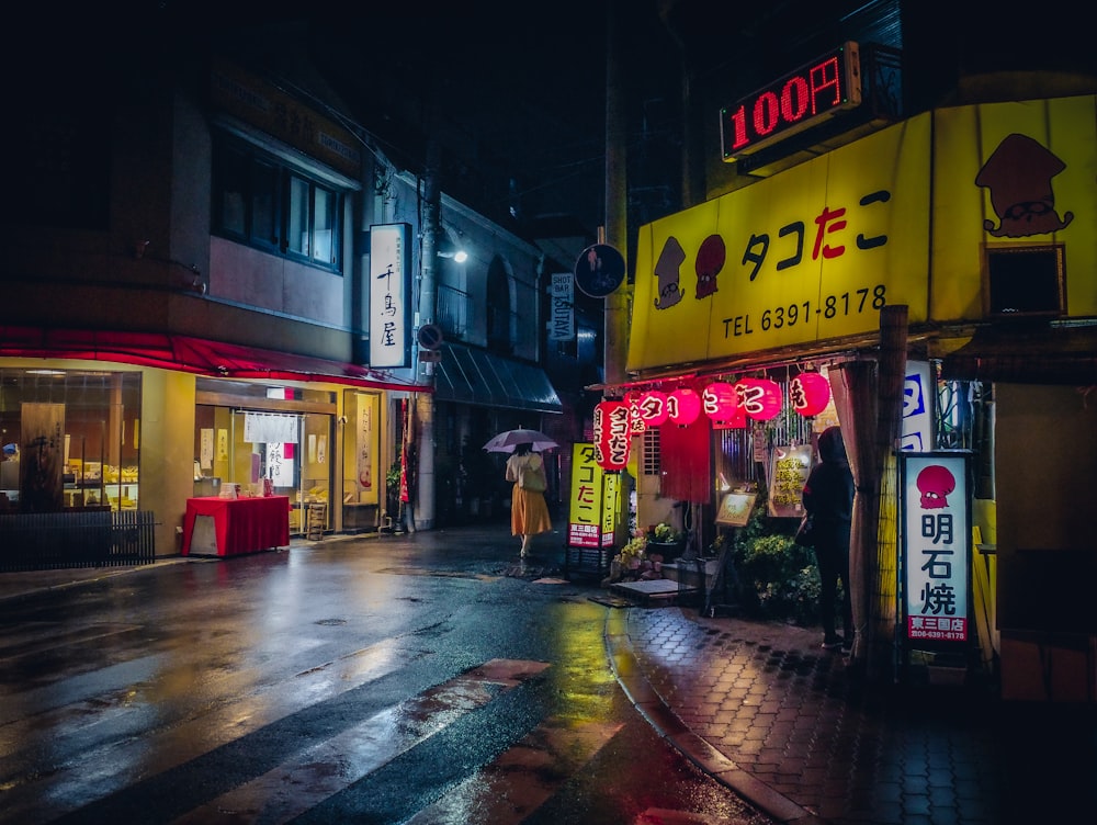 a wet city street at night with people walking by