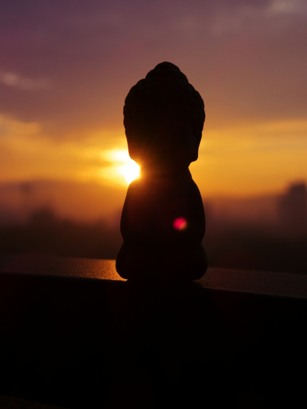 the sun is setting behind a statue of a person