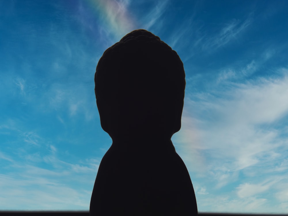 a silhouette of a person with a rainbow in the background