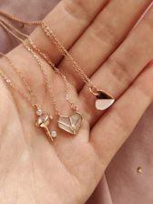 a woman's hand holding four different necklaces