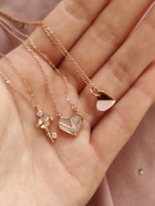 a woman's hand holding four different necklaces