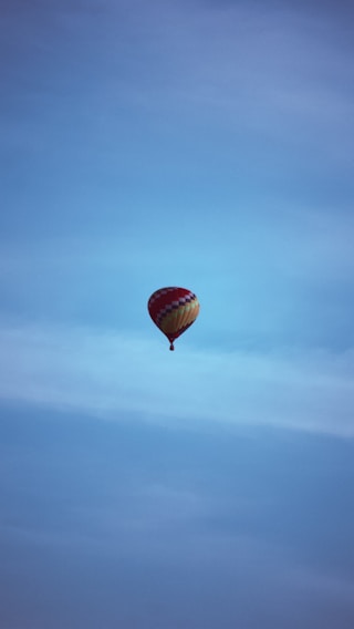 A colorful hot air balloon soaring peacefully over the sprawling Delhi skyline at sunrise.