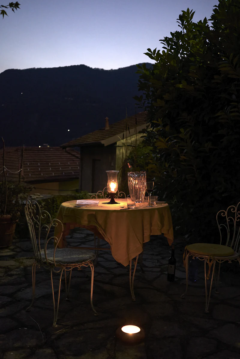 A single table laid for two, lit by a hurricane lamp at night