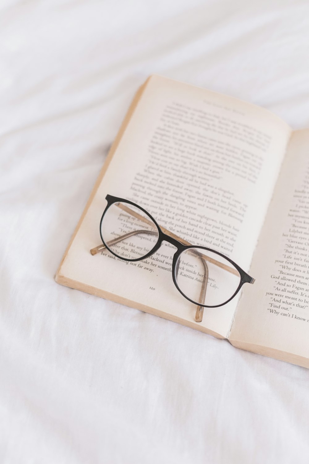 an open book with glasses on top of it