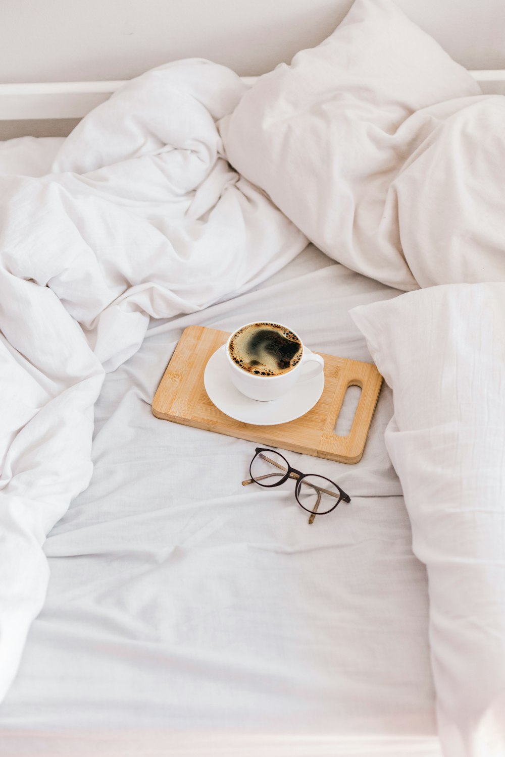 a cup of coffee on a tray on a bed