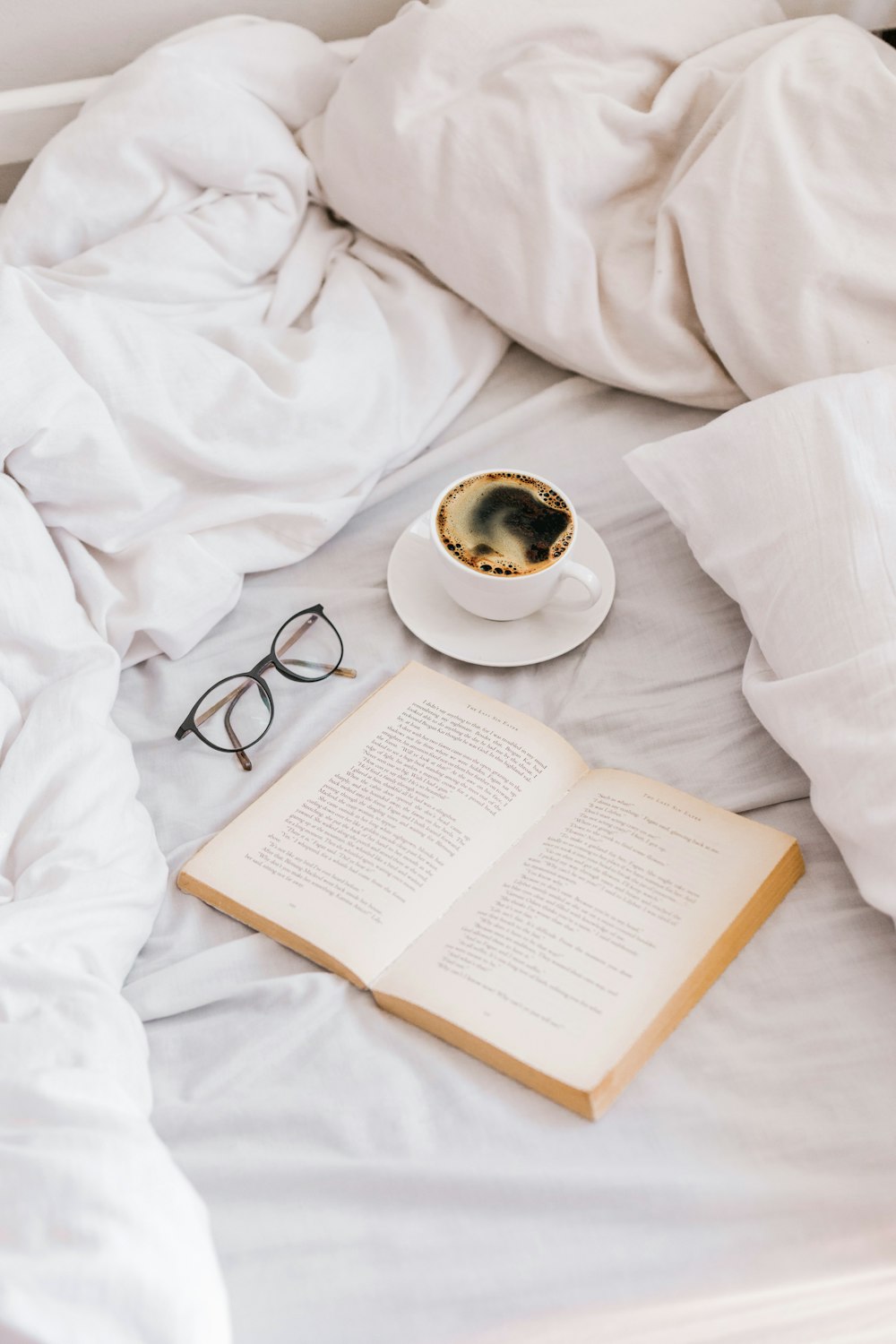 a cup of coffee and a book on a bed