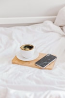 A serene shot of a luxury coffee cup on a white table beside a sleek smartphone.