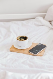 A serene shot of a luxury coffee cup on a white table beside a sleek smartphone.