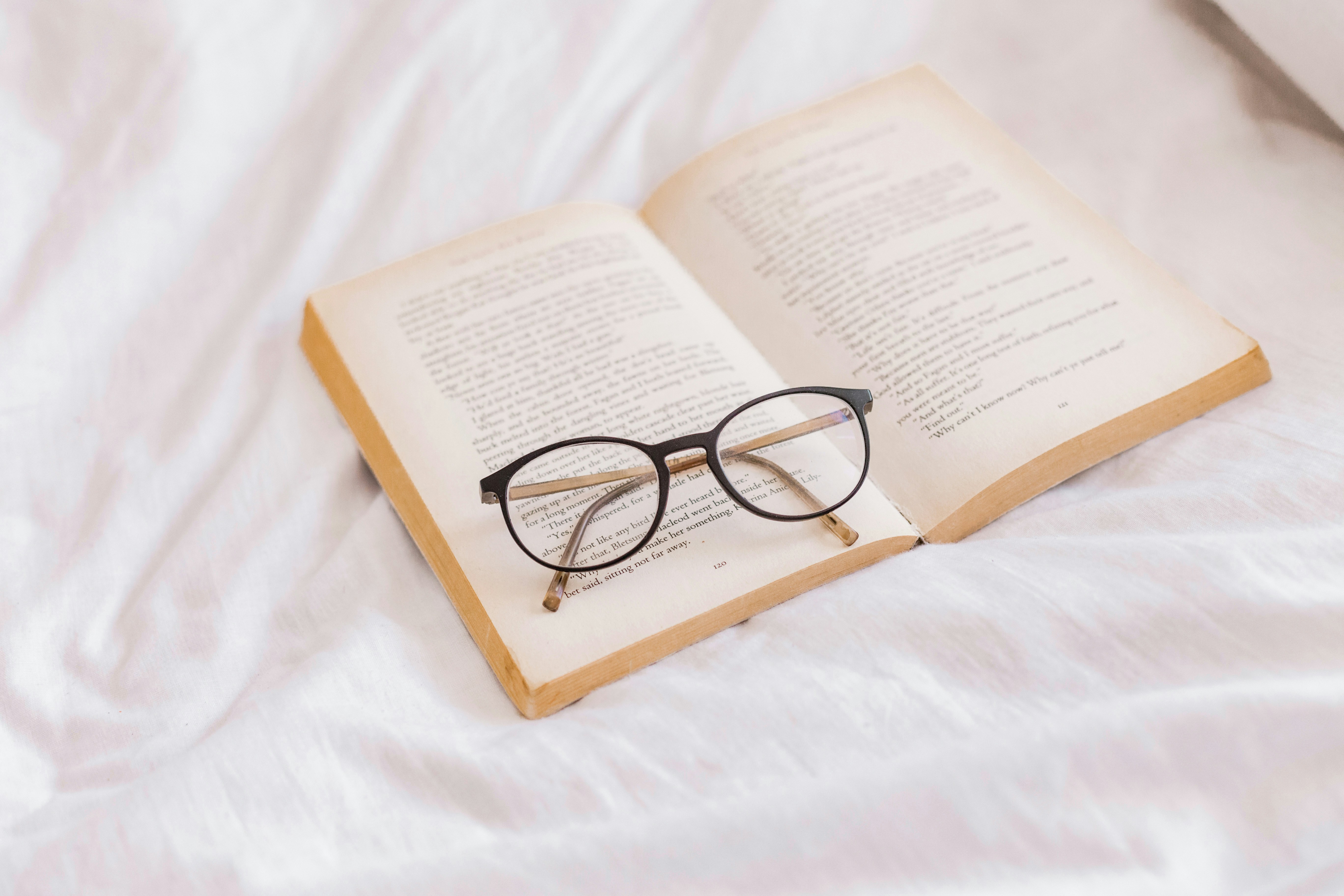 an open book with glasses on top of it