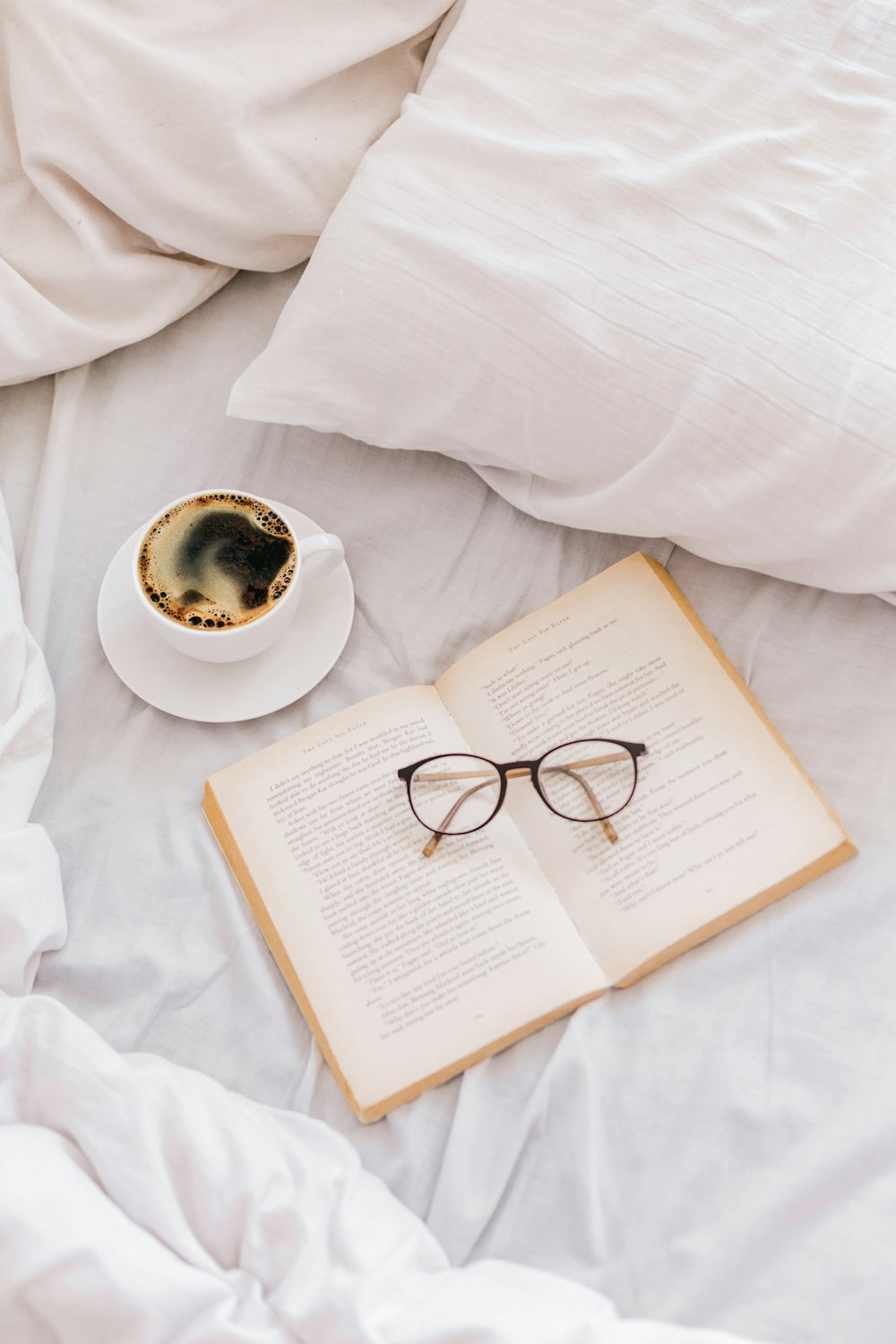 a cup of coffee and a book on a bed