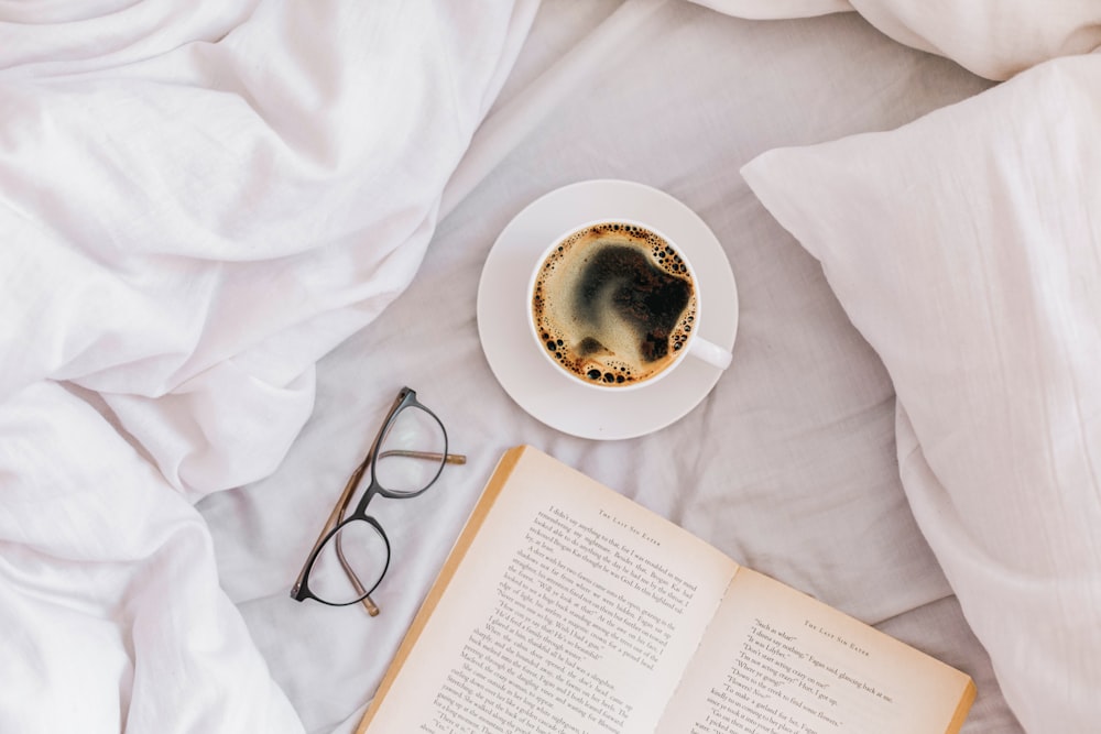 a cup of coffee and a book on a bed