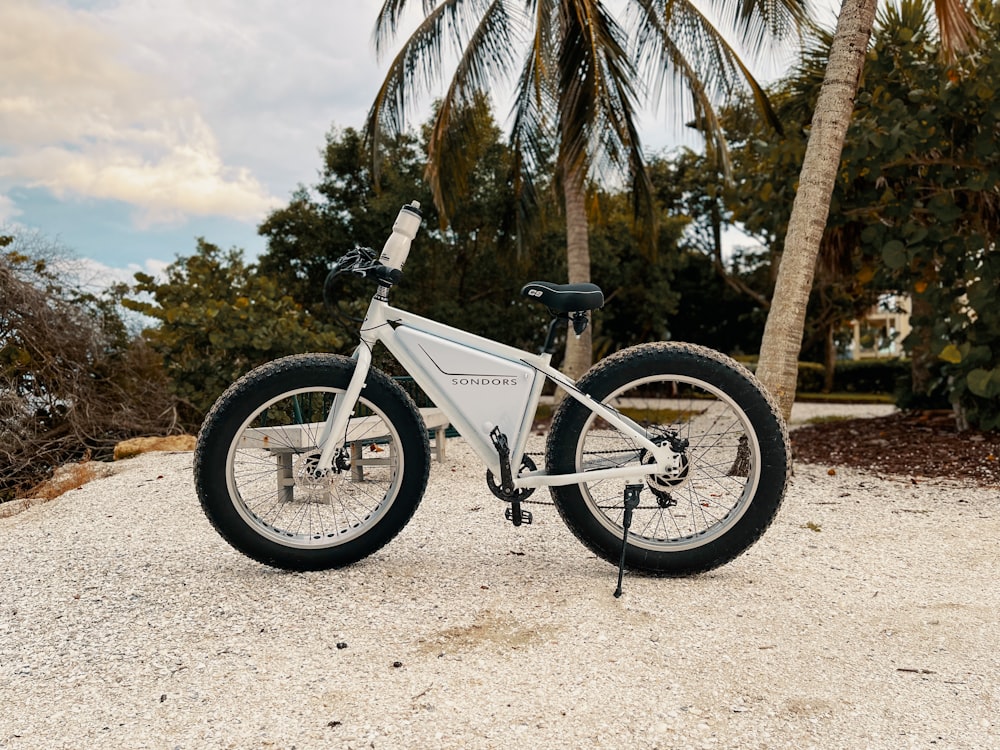 a white bicycle parked on top of a sandy beach