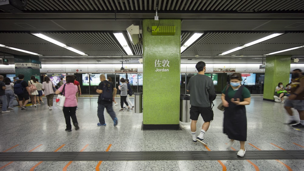 Un grupo de personas de pie alrededor de una estación de metro