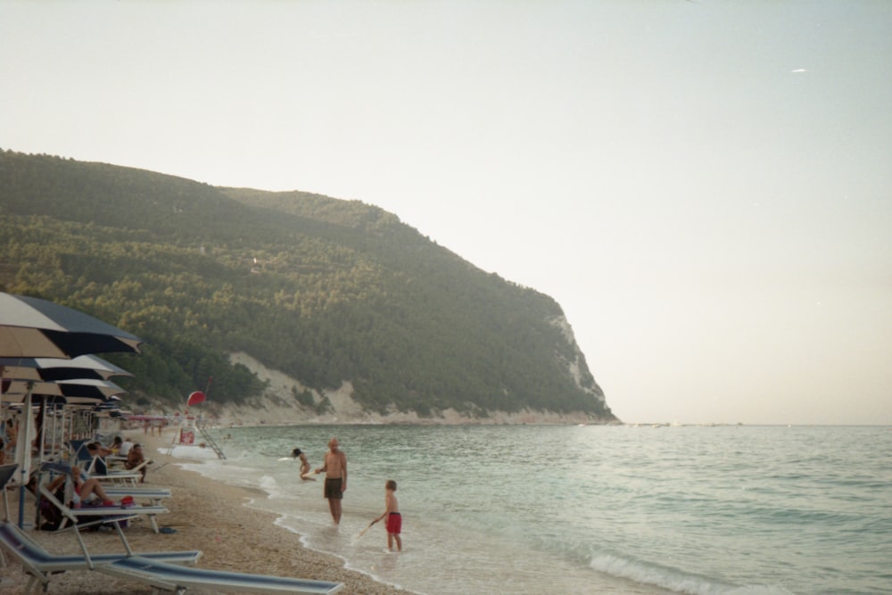 a group of people walking along a beach next to the ocean