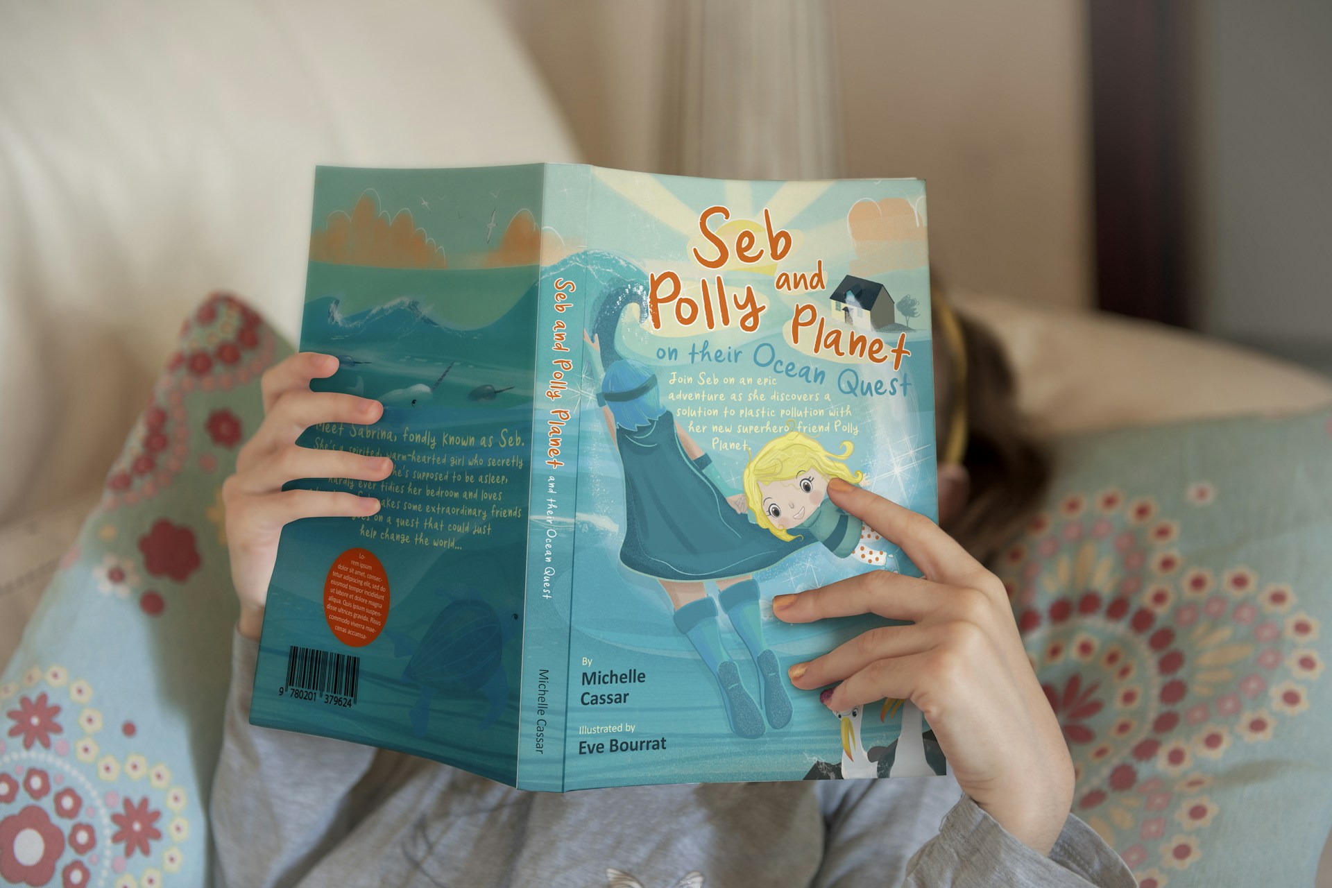 a little girl is reading a book on a couch