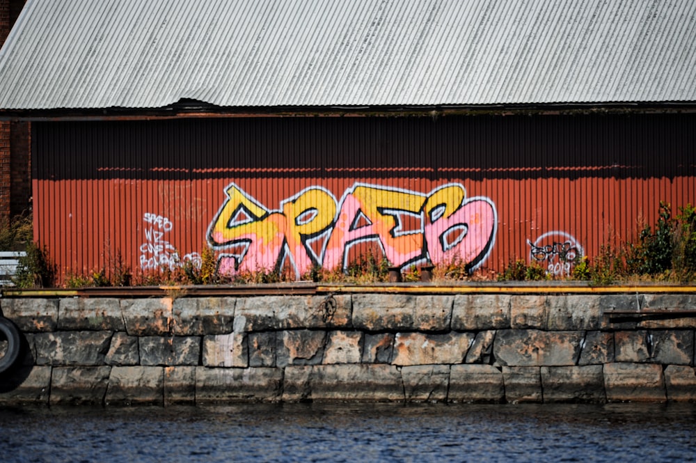 a brick wall with graffiti on it next to a body of water