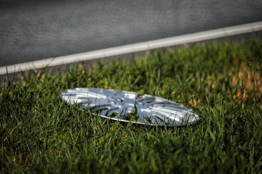 a white frisbee laying in the grass next to a road