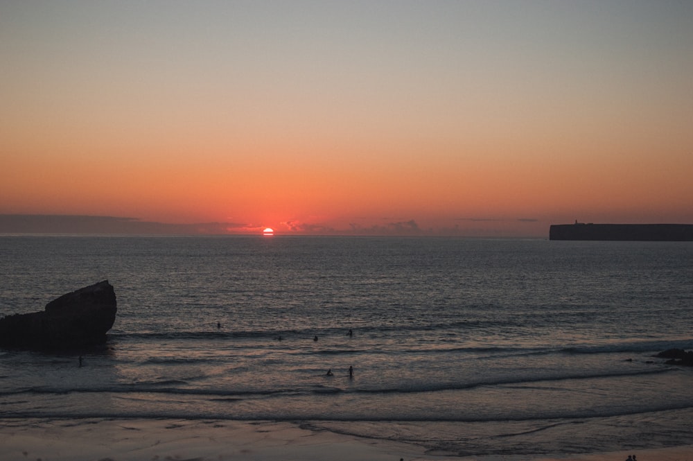 Il sole sta tramontando sull'oceano con una barca in lontananza