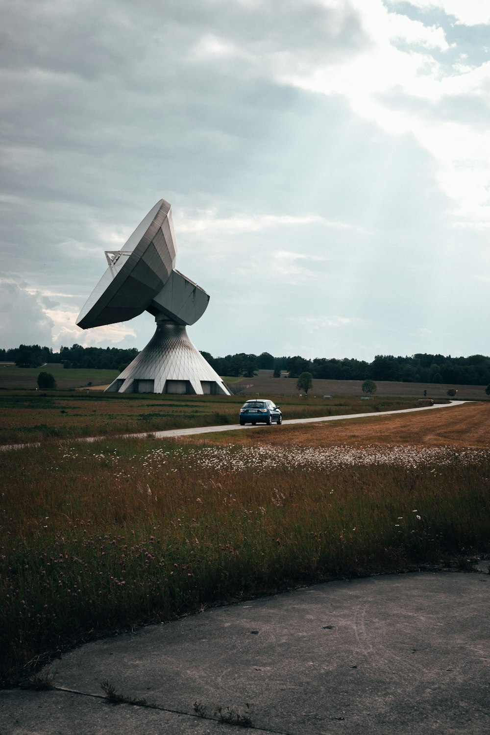 a car is parked in front of a large satellite dish