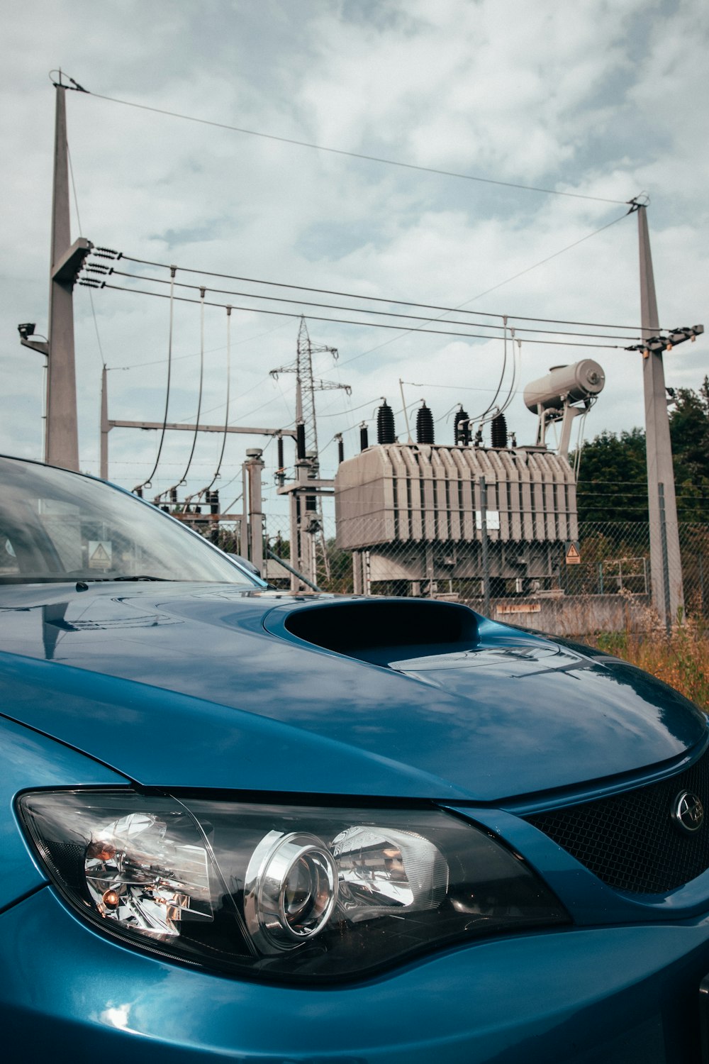 a blue car parked in front of a power line