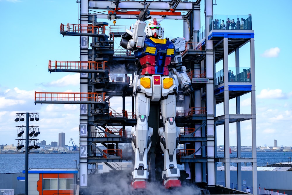 a giant robot standing on top of a building next to a body of water