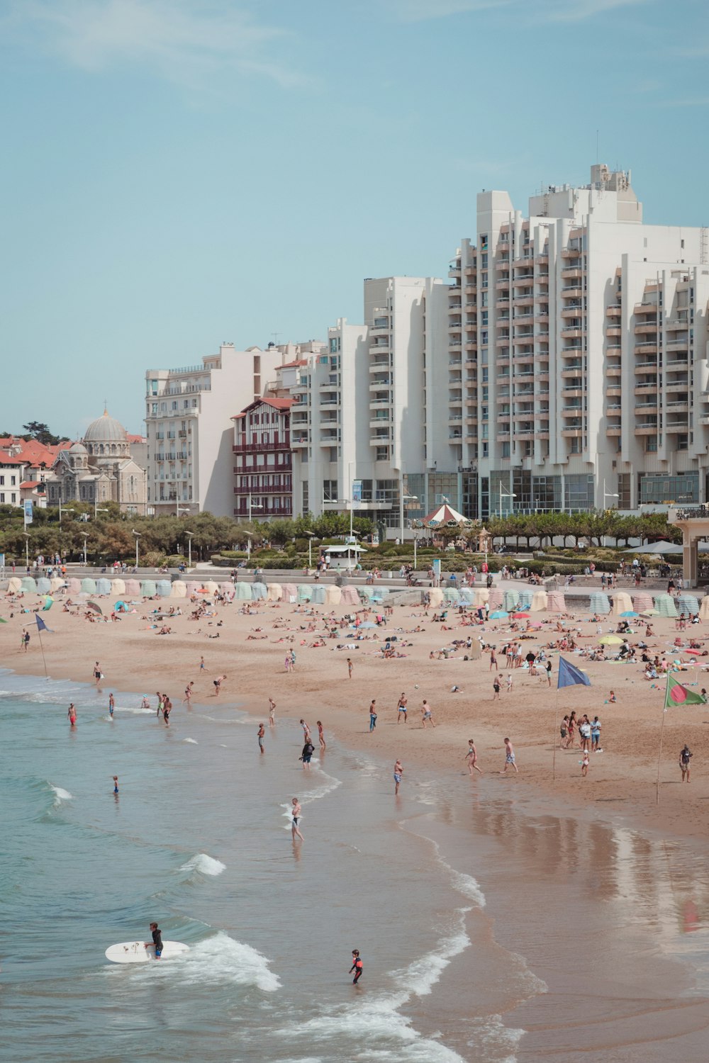 a beach with many people on it and buildings in the background
