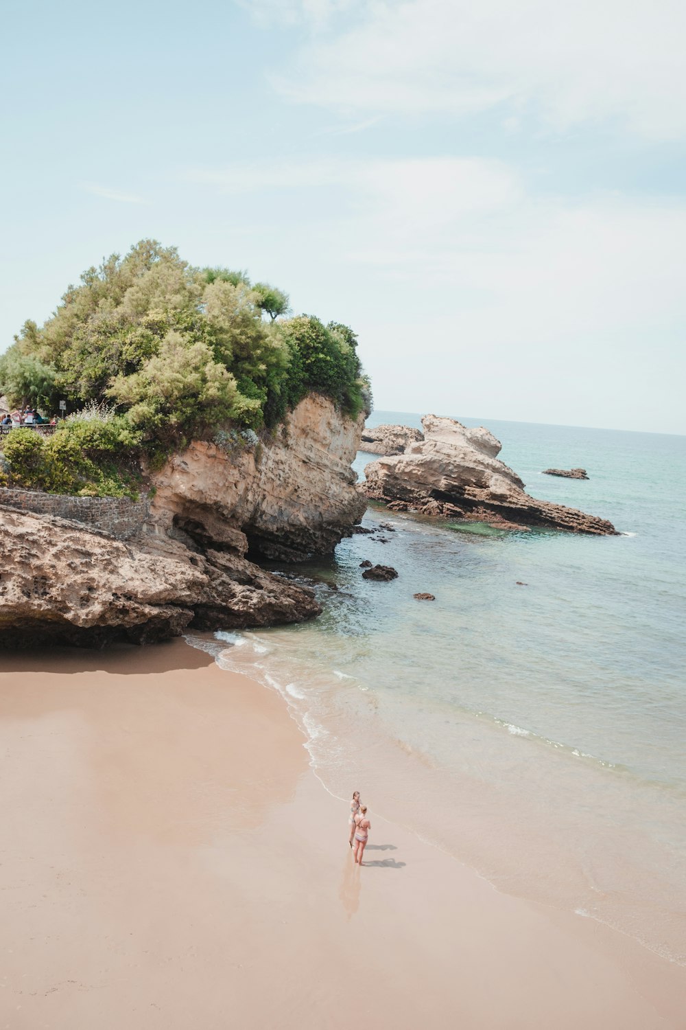 a couple of people standing on top of a sandy beach