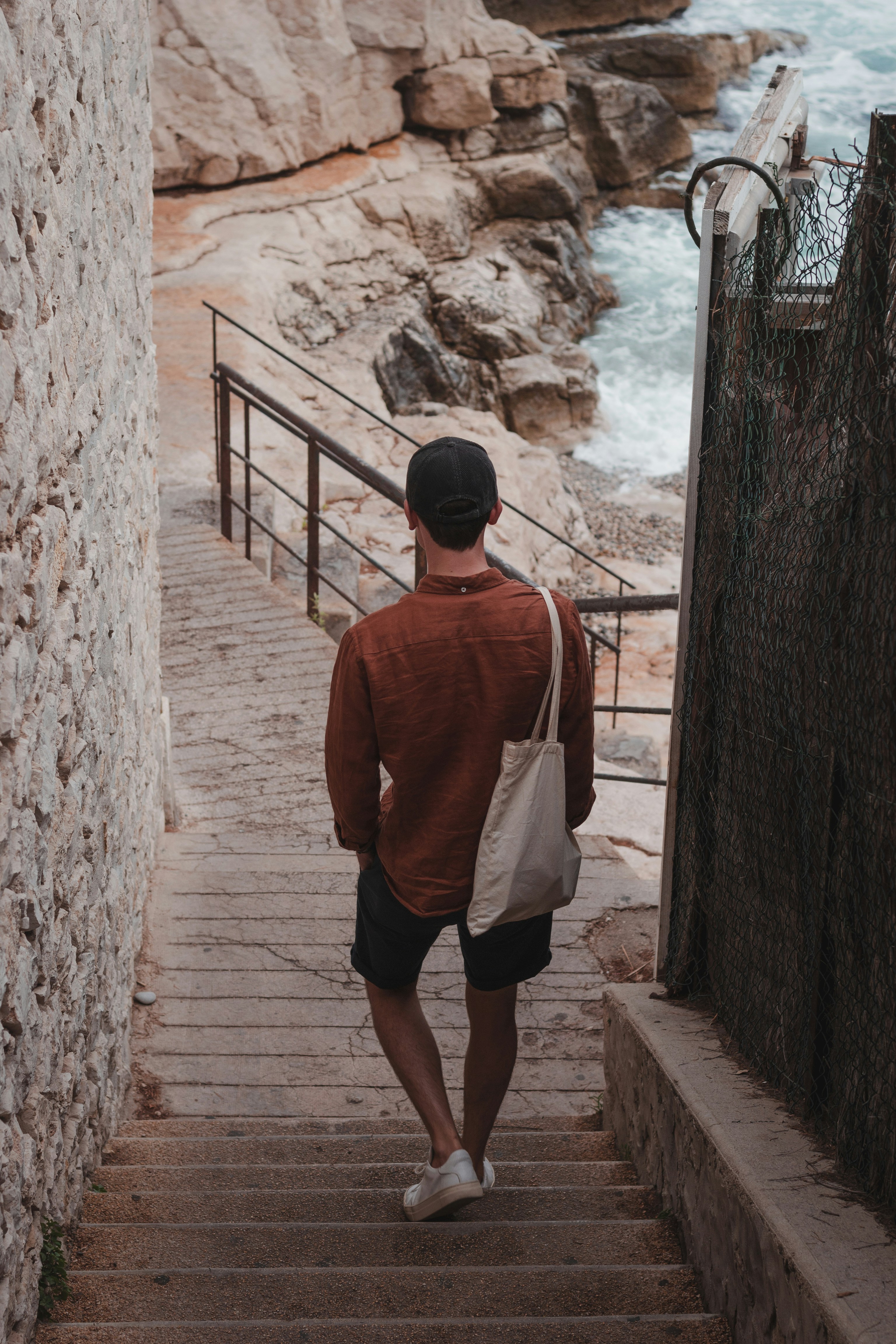 a man walking up a set of stairs next to the ocean