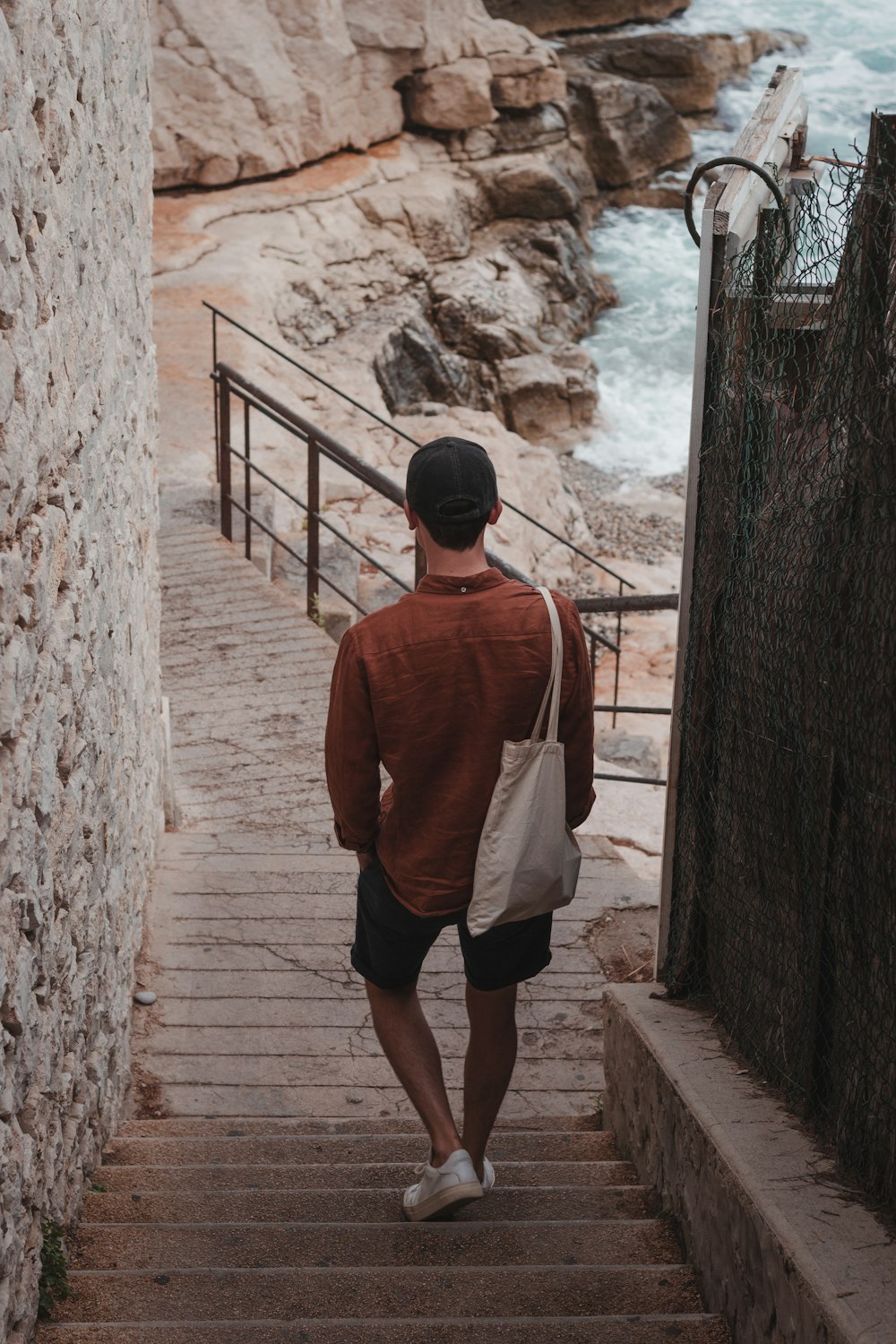a man walking up a set of stairs next to the ocean