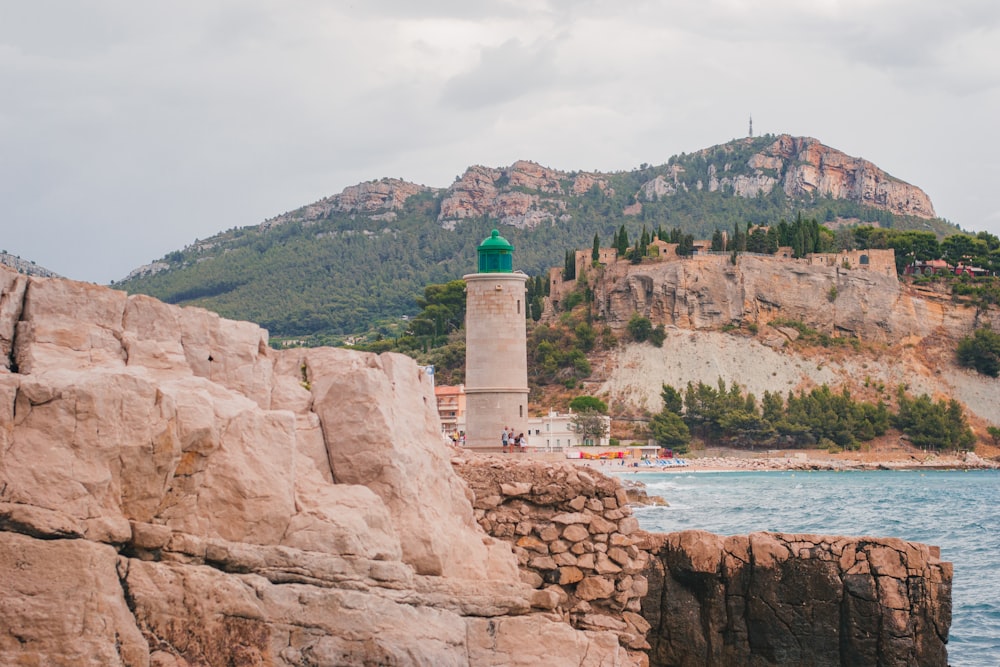 a lighthouse on a rocky shore with a mountain in the background