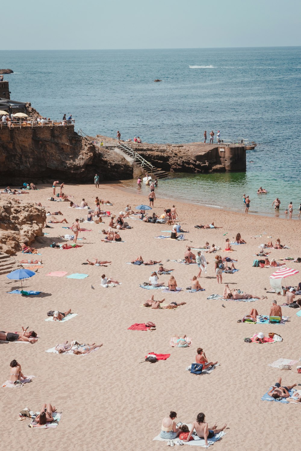 a crowded beach with people laying and standing on it