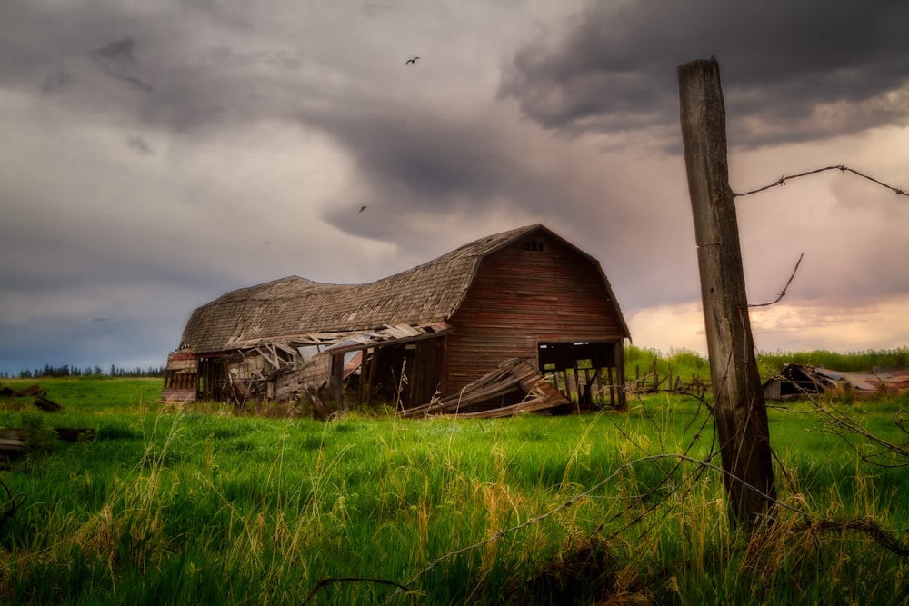 a barn in a field with a stormy sky in the background