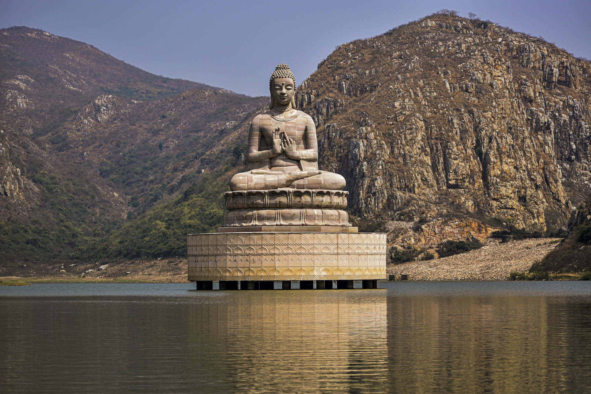 a buddha statue sitting in the middle of a body of water