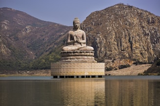 a buddha statue sitting in the middle of a body of water