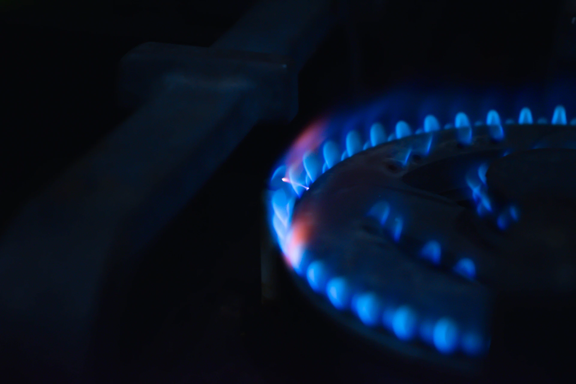 A gas burner's blue flame glowing in the dark