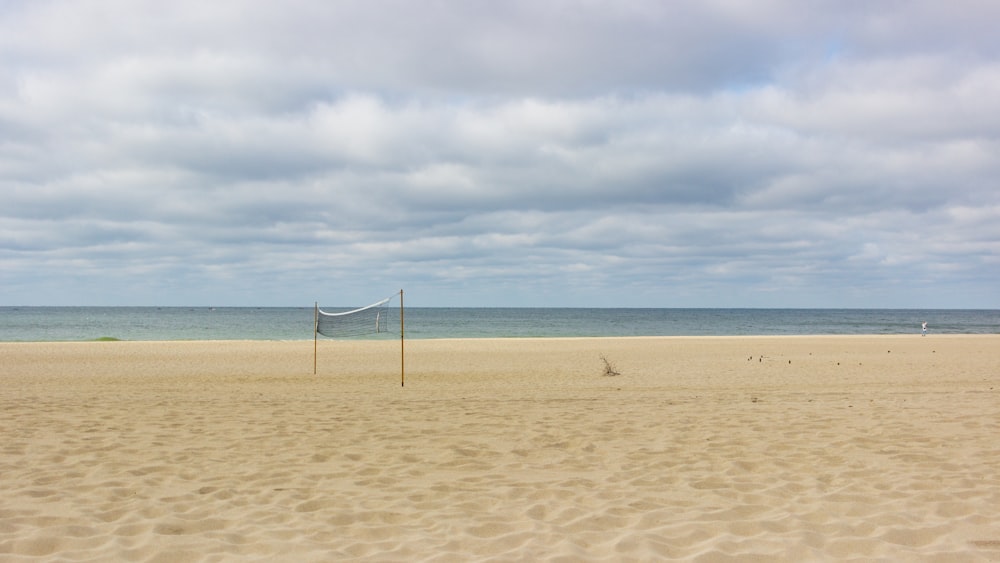 a volleyball net on a sandy beach with the ocean in the background