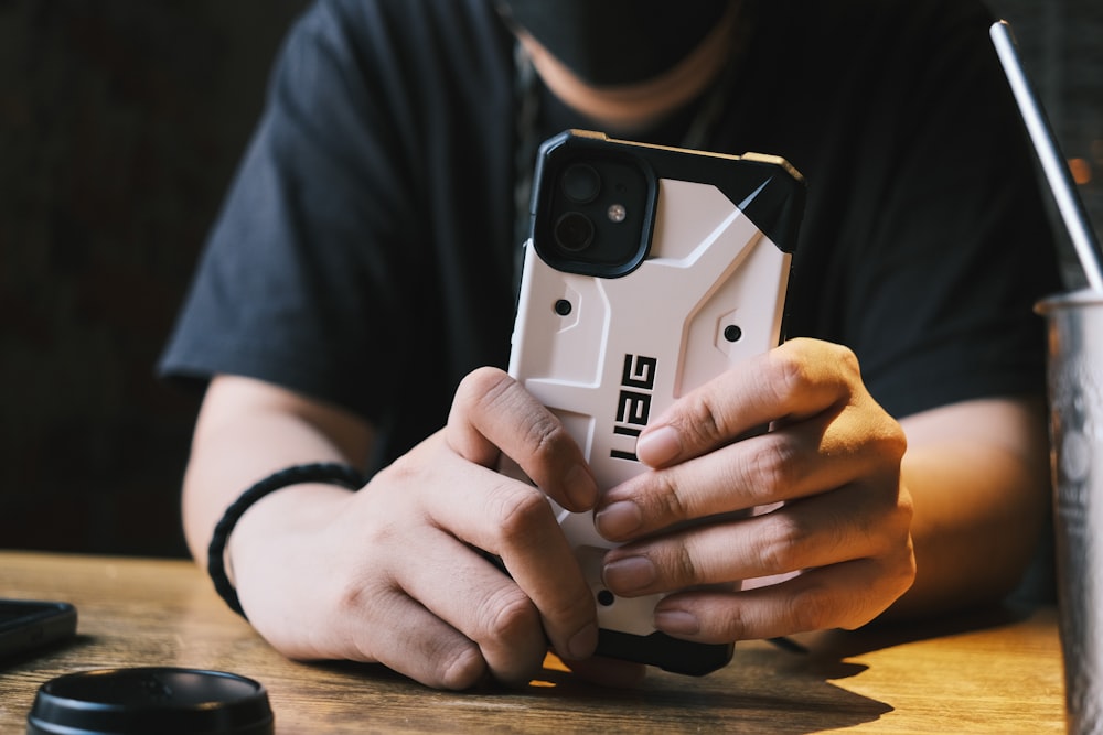 a man is holding a cell phone while sitting at a table